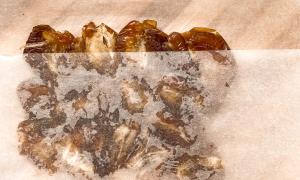 Dátiles aplastados con papel manteca sobre una tabla de madera.