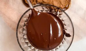 Cuchara de chocolate derretido, en el fondo mantequilla de maní con miso extendida sobre los dátiles